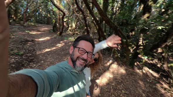 Happy adult couple enjoy together outdoor leisure activity in the forest wood enjoying the nature