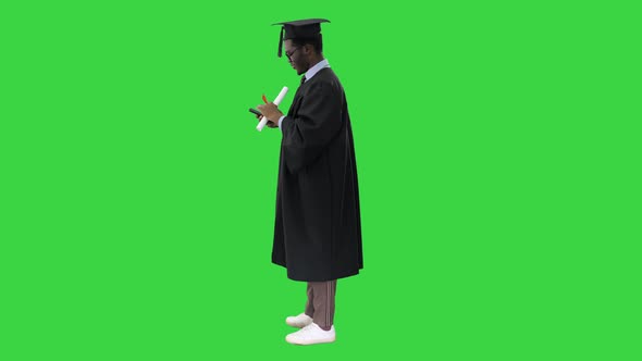 Happy African American Male Student in Graduation Robe Taking Phone Selfies with His Diploma on a