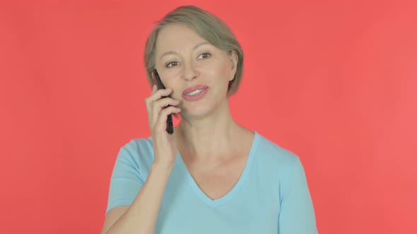 Old Woman Talking on Phone on Red Background
