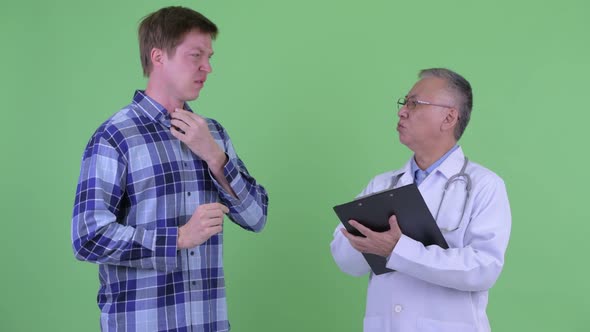 Mature Japanese Man Doctor with Young Man Having Consultation for Sore Throat