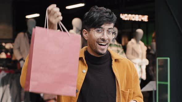 Closeup Young Indian Male Shopper Customer Shopaholic Standing Posing Looking at Camera Showing Gift