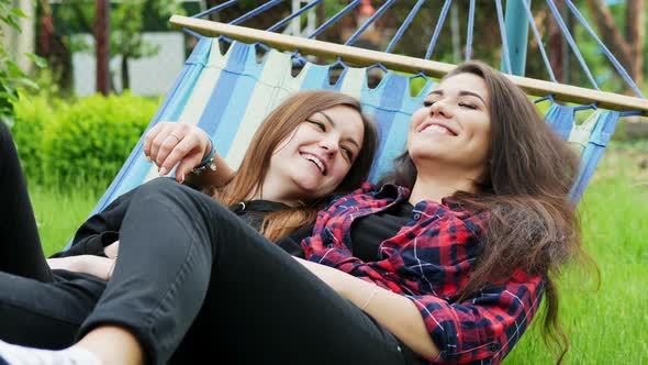 Lesbian Couple Lie in Hammock in Garden