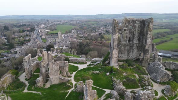 Legendary Corfe Castle perched on hill and village in background, County Dorset in England. Aerial r
