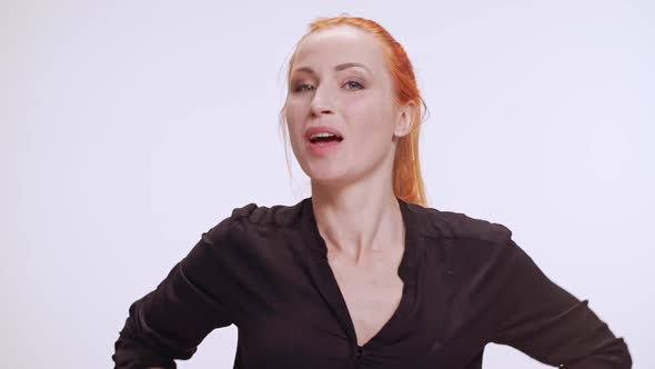 Middleaged Caucasian Woman with Colored Orange Hair and Dark Brown Shirt Playing with Breast