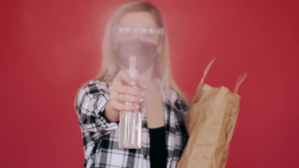 Woman in Protective Glasses and Mask Is Spraying Antiseptic