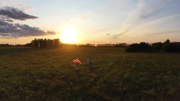 The Mother and Boy Run with a Kite on a Green Field