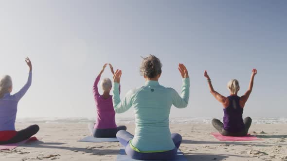 Athletic women performing yoga in the beach