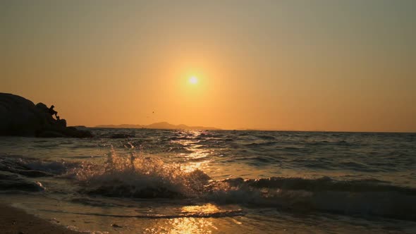 Beautiful orange sunset on background of sea with waves