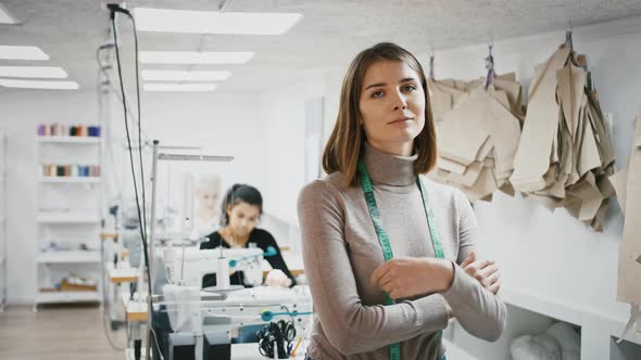 Female Tailor with Tape Measure on Neck is Smiling While Posing at Workshop Seamstresses Working at