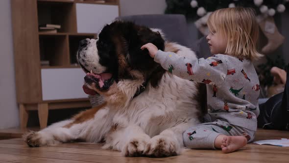 Happy Little Boy in Pajamas for Christmas Is Telling Secrets in the Ear of His Friend Big Dog