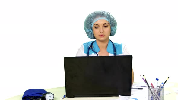 Smiling Doctor Sitting at the Computer on White Background