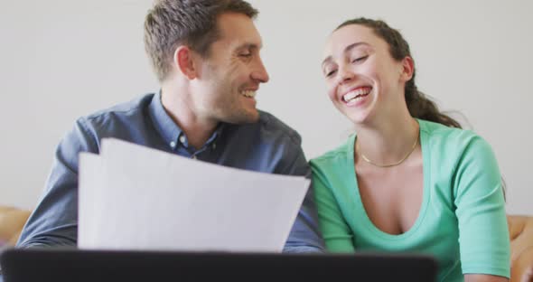 A young caucasian couple talking and paying their bills using a laptop