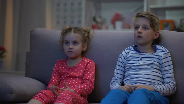 Brother Hugging Scared Sister While Watching Horror Film Together Night, Family