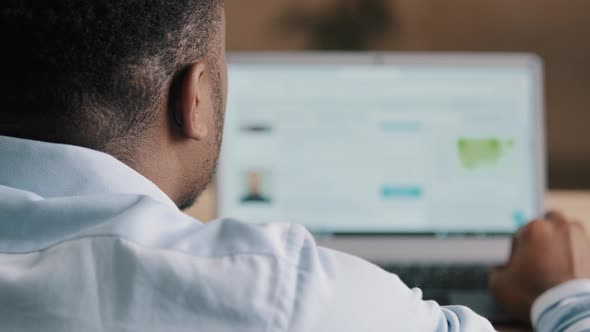 Back View of Unknown African American Man Freelancer Blogger Technical Administrator in Blue Shirt