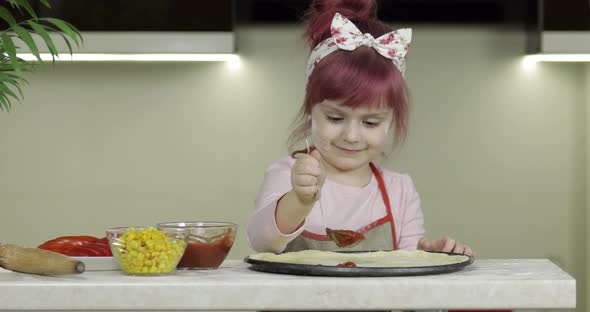 Cooking Pizza. Little Child in Apron Adding Tomato Sauce To Dough in Kitchen