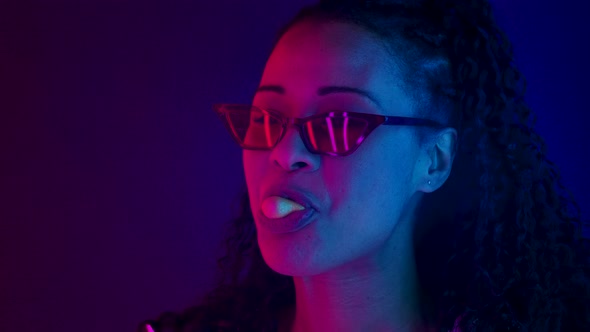 Portrait of a Young Lovely Female African American in Stylish Sunglasses Smiling, Chewing Gum and