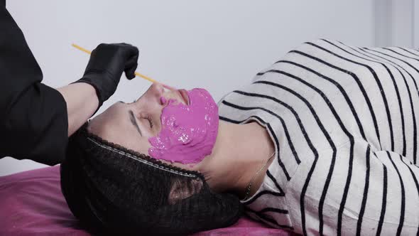 Alginate mask application process. A female hands of a beautician holding spatula