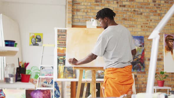 African american male painter painting on canvas in artist studio