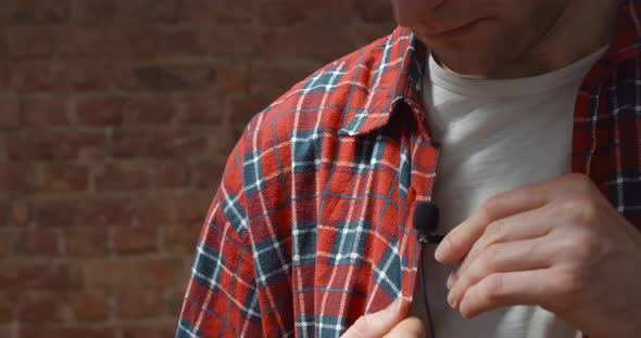 Close Up of Man Clipping Tieclip Microphone To His Shirt