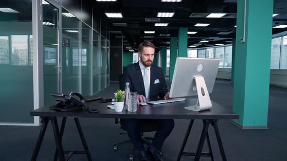 Working Overtime Young Businessman Sits at a Desk in the Office and Works on a Pc Manager Works on