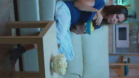 Vertical Video: Woman Sitting on Couch and Watching Tv