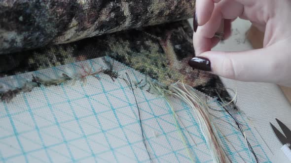 Cross stitching. Woman makes embroidery beautiful picture of nature.