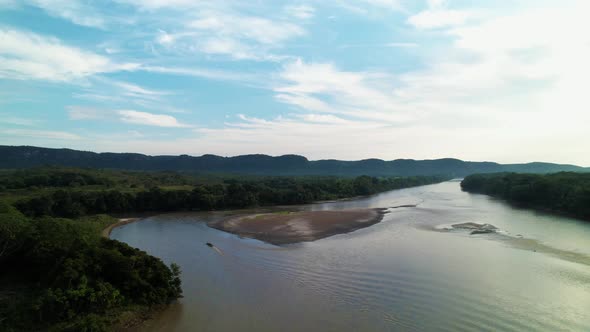 Motor boat passing along the river with a crew of tourists. Shores of green rainforest, horizon with