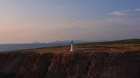 Breathtaking circle shot of lighthouse on majestic rocky cliff, golden hour