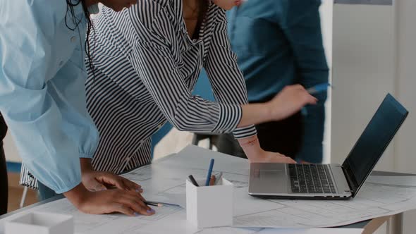 Close Up of Women Architects Looking at Laptop and Blueprints Plans on Table