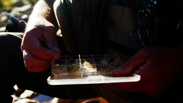 Fly fisherman removing bait from tackle box