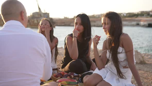 Concentrated Caucasian Woman and Girls Listening to Man Talking in Sunshine on Family Picnic