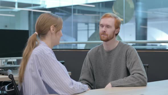 Young Woman Talking to Young Man in Office