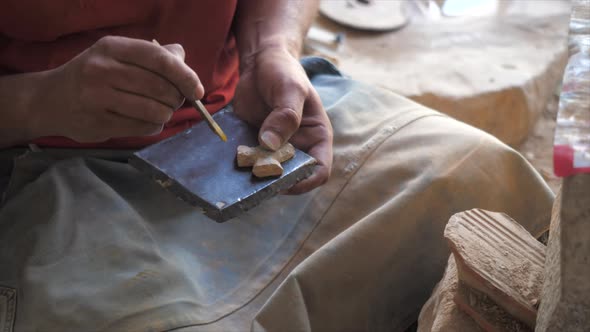 Rotating shot of a carpenter imprinting the design that he made on a wooden base so that he can make