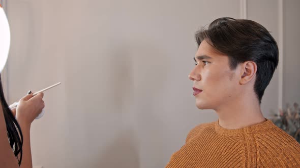 Makeup Studio - Makeup Artist Applying Red Lipstick on the Lips of Handsome Male Model