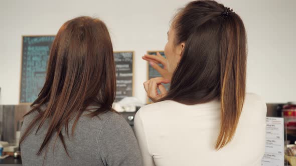 Two Women Discuss the Menu and Choose Food in a Cafe Standing at the Bar Counter.