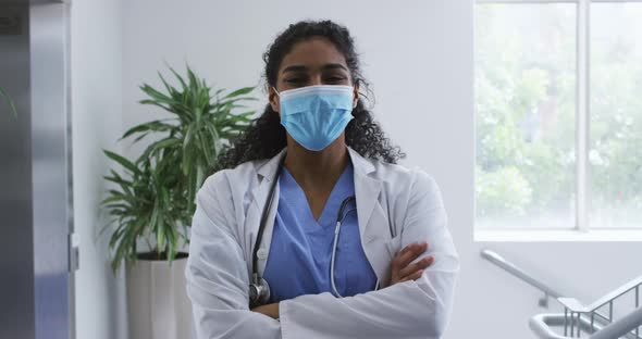 Portrait of asian female doctor wearing face mask standing with arms crossed in hospital