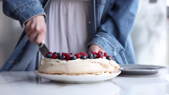 woman slice meringue cake on the table