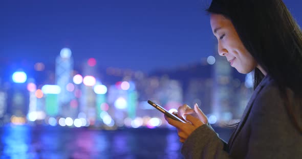 Business woman using cellphone in Hong Kong city at night