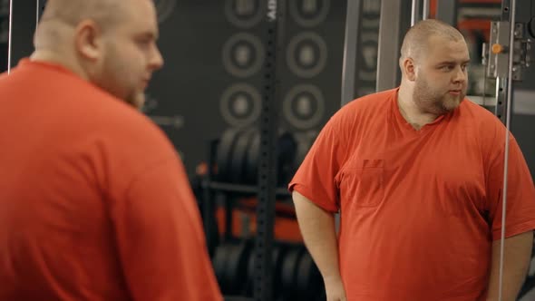 Calm Man Looks at Himself in the Mirror of the Sport Gym