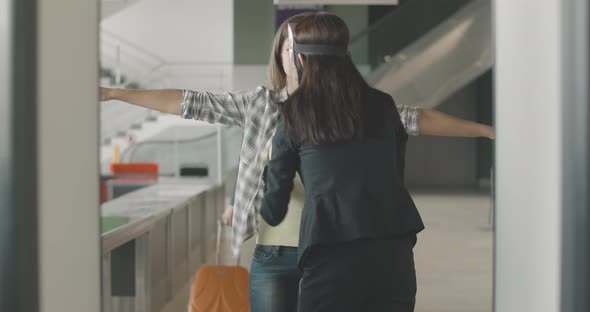 Female Employee Examining Young Woman at Security Gates in Airport While Mid-adult Man Walking with