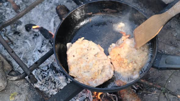 Fried Pork Chops in Oil in a Frying Pan Over Fire Outdoor Cooking Fatty Meat