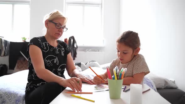 Mature Woman Granny with Grandchild Preschool Girl Drawing Together at Home