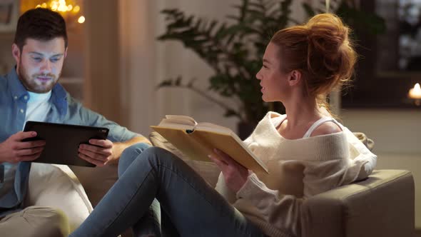 Couple with Tablet Computer and Book at Home