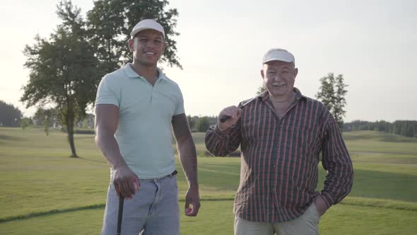 Portrait Mature Caucasian Man and Young Middle Eastern Man Playing Golf on the Golf Field