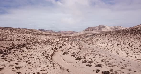 Path road in the middle of a mountains sand desert with blue bright sky in background. Arid climate