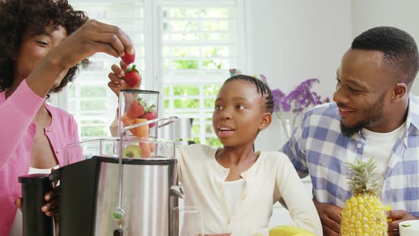 Mother and daughter putting strawberries in juicer