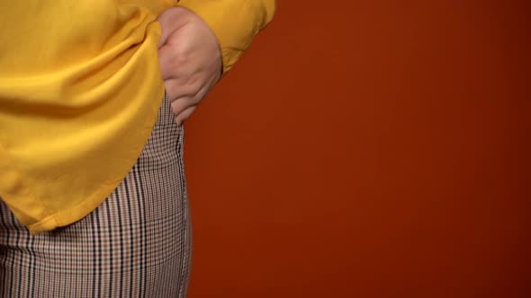 Front View on Body Part of Young Female in Yellow Blouse and Trousers on Orange Background with