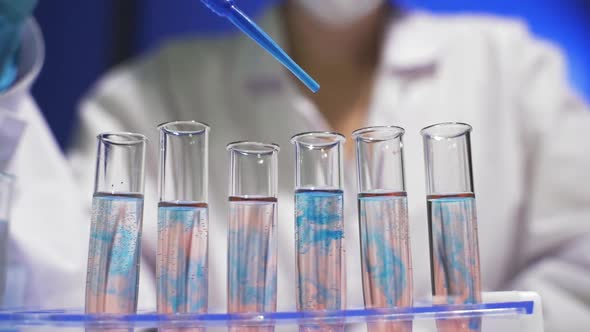 Lab Assistant Adding Blue Liquid in Test Tube Monitoring Chemical Reaction