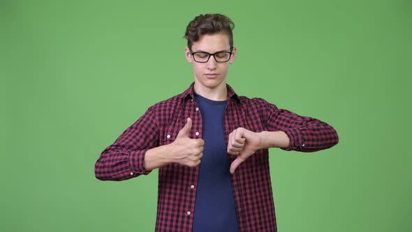 Young Handsome Teenage Nerd Boy Choosing Between Thumbs Up and Thumbs Down