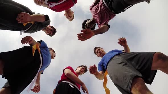 A group of young men playing flag football on the beach.